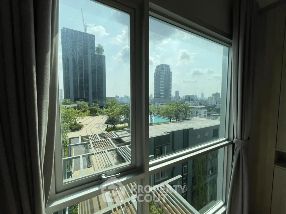 Stunning cityscape view from modern apartment window with lush greenery and urban skyline.