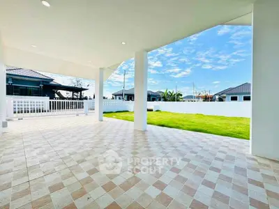 Spacious covered patio with tiled flooring and lush green lawn view