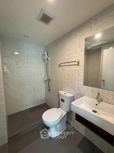 Modern bathroom with sleek fixtures and tiled walls, featuring a shower, toilet, and sink.