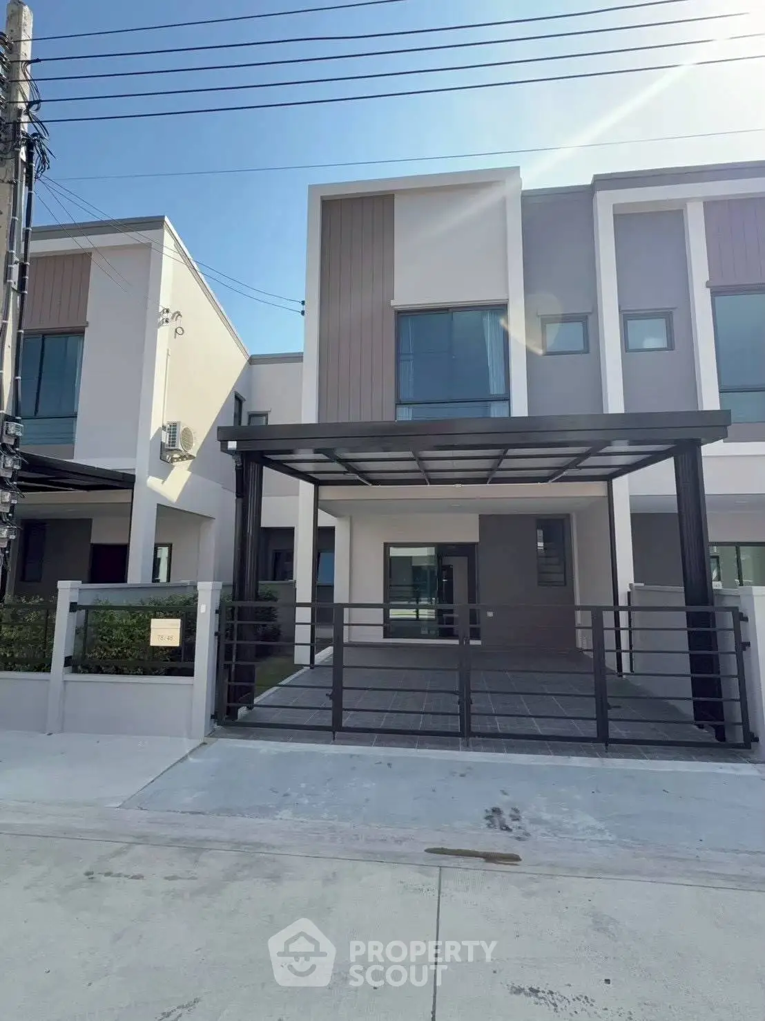 Modern townhouse exterior with sleek design and spacious driveway under clear blue sky.