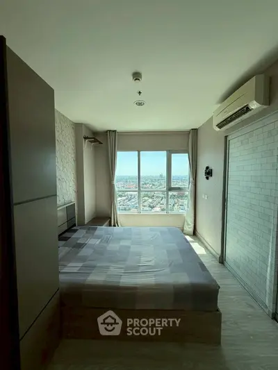 Modern bedroom with city view, featuring large window and air conditioning unit.