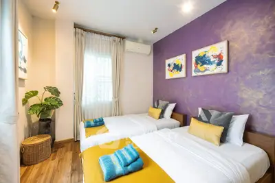 Charming bedroom with twin beds, vibrant purple accent wall, and modern decor.