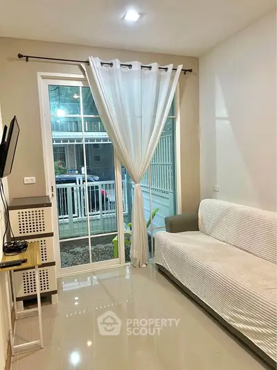 Bright living room with modern decor and large window overlooking garden view.