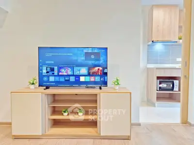 Modern living room with sleek TV stand and view into stylish kitchen area.