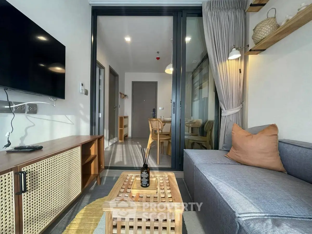 Modern living room with stylish decor and open view to dining area, featuring cozy sofa and wall-mounted TV.
