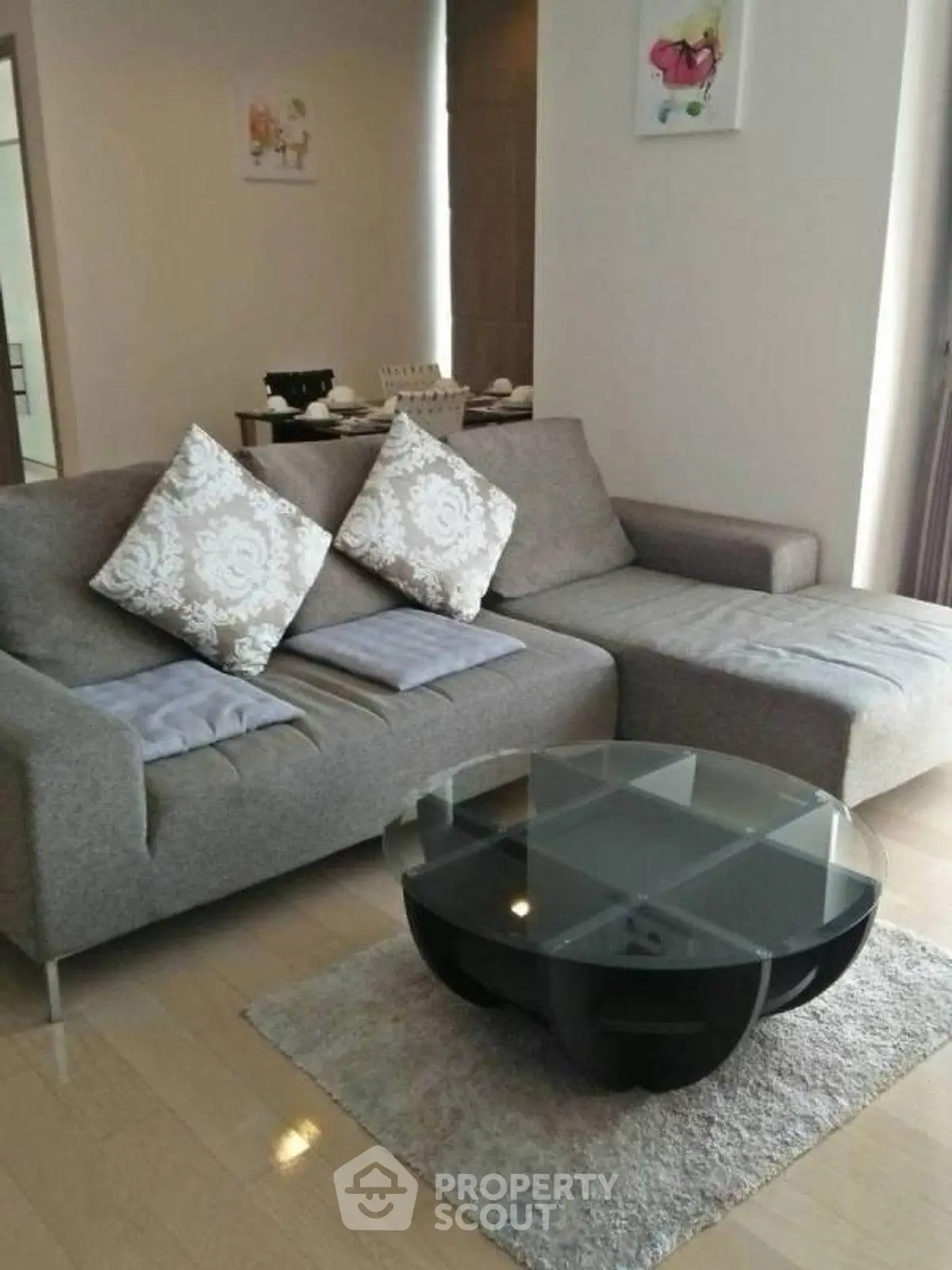 Modern living room with stylish gray sofa and glass coffee table on wooden floor.