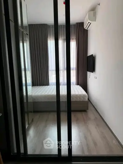 Modern bedroom with floor-to-ceiling windows and sleek furnishings in a contemporary apartment.