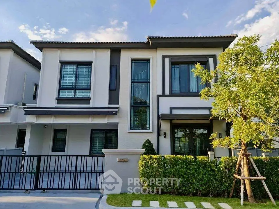Modern two-story house with large windows and landscaped front yard in a serene neighborhood.