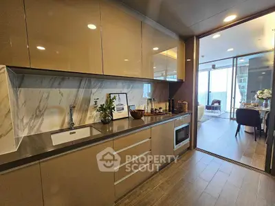 Modern kitchen with sleek cabinetry and open layout leading to dining area