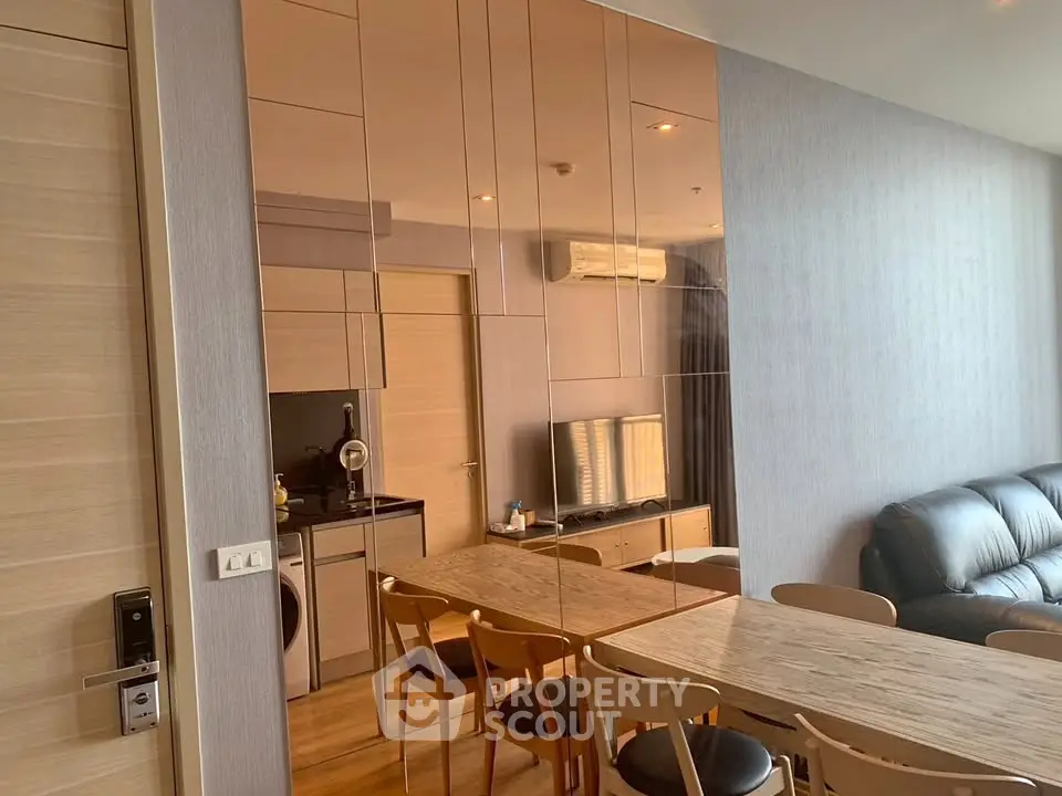Modern living room with sleek furniture and mirrored wall in a stylish apartment.
