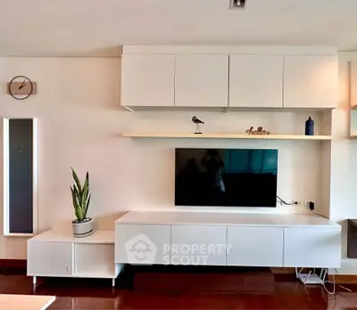 Modern living room with sleek white cabinetry and wall-mounted TV, perfect for stylish urban living.