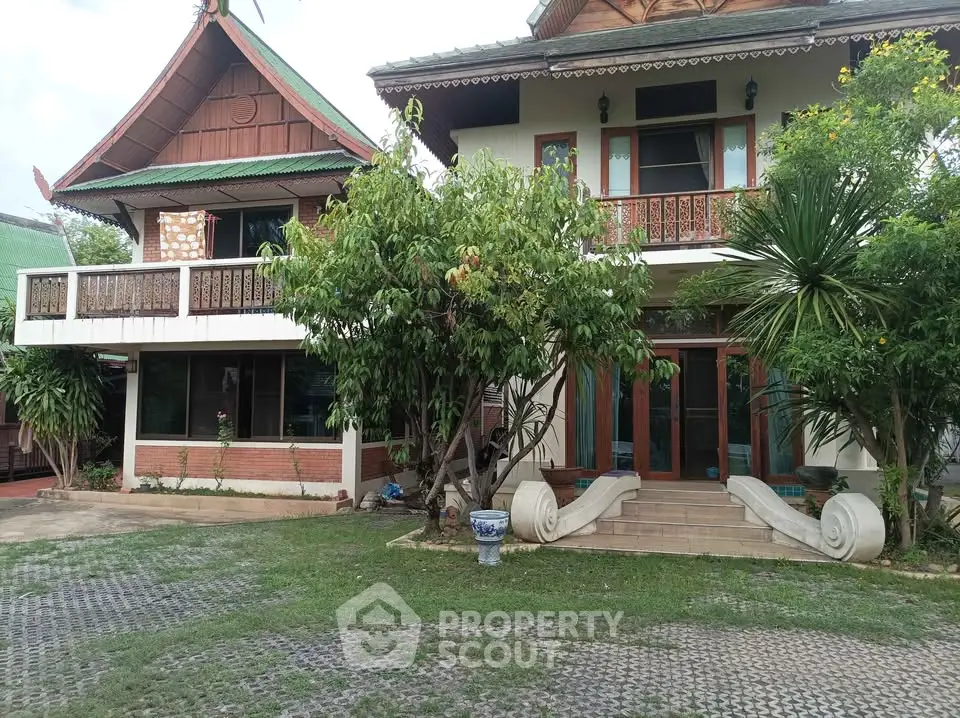 Charming traditional Thai-style house with lush greenery and unique architectural details.