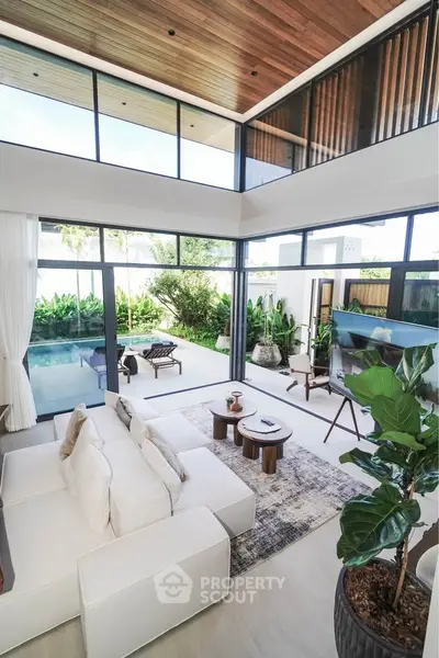 Luxurious modern living room with high ceilings and pool view, featuring elegant decor and abundant natural light.