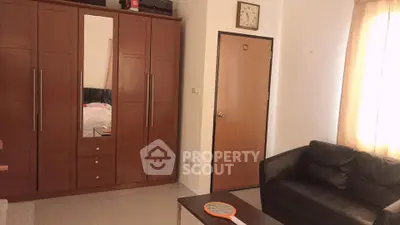 Cozy living room with brown wardrobe and black sofa, perfect for relaxation.