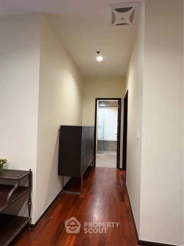 Elegant hallway with wooden flooring and modern decor leading to a spacious room.