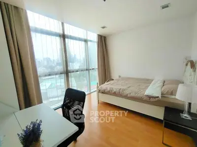 Bright bedroom with city view, large windows, and modern furnishings in a high-rise apartment.