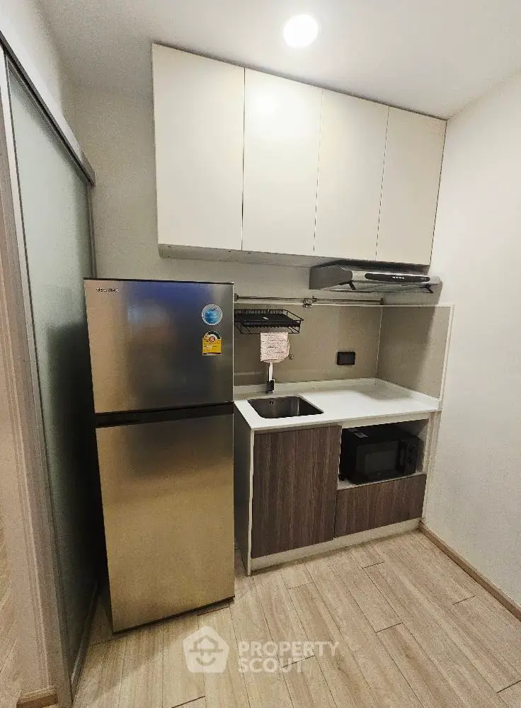 Compact modern kitchen with stainless steel fridge and microwave
