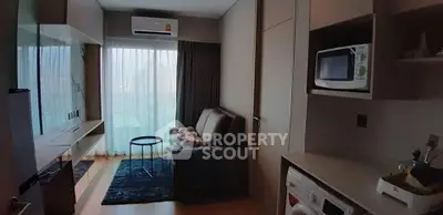 Modern compact living room with sofa, TV, and kitchen appliances in cozy apartment.