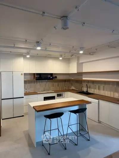 Modern kitchen with sleek white cabinetry, wooden countertops, and stylish bar stools.