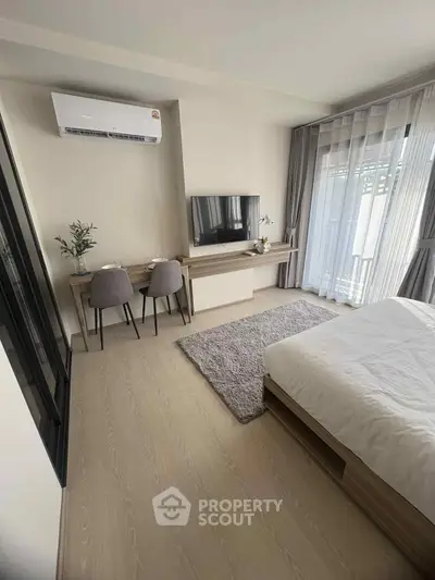 Modern bedroom with sleek design, featuring a wall-mounted TV, air conditioning, and a cozy workspace.