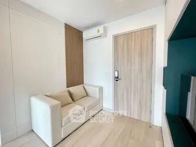 Modern living room with sleek design and cozy sofa, featuring minimalist decor and air conditioning.