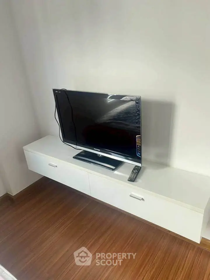 Modern living room with sleek TV setup on white console and wooden flooring.