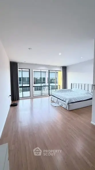 Spacious bedroom with large windows and modern decor in a bright apartment.