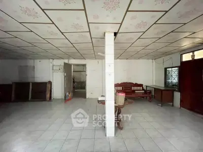 Spacious interior with tiled floor and floral ceiling, featuring a wooden bench and table, ideal for creative renovation.
