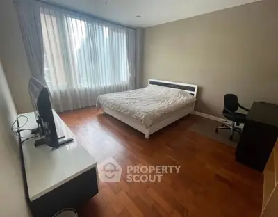 Spacious bedroom with large window and wooden flooring in modern apartment