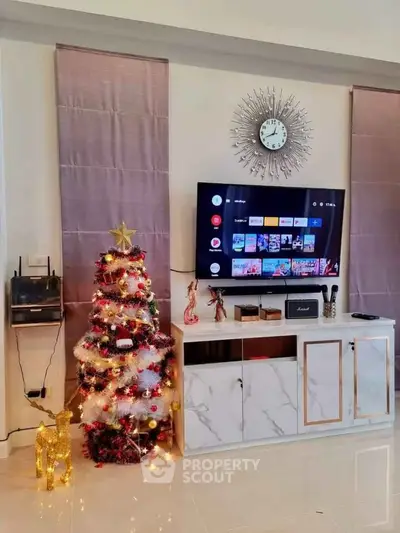 Stylish living room with modern decor, featuring a TV, elegant clock, and festive Christmas tree.
