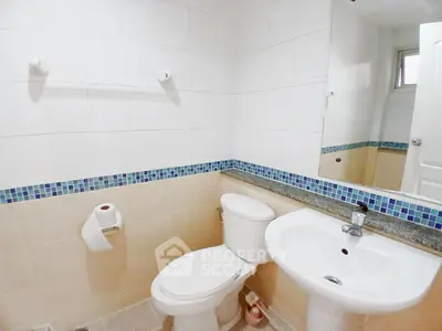 Modern bathroom with white fixtures and blue tile accents