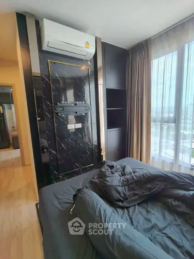 Modern bedroom with stylish black marble accent wall and large window offering natural light.