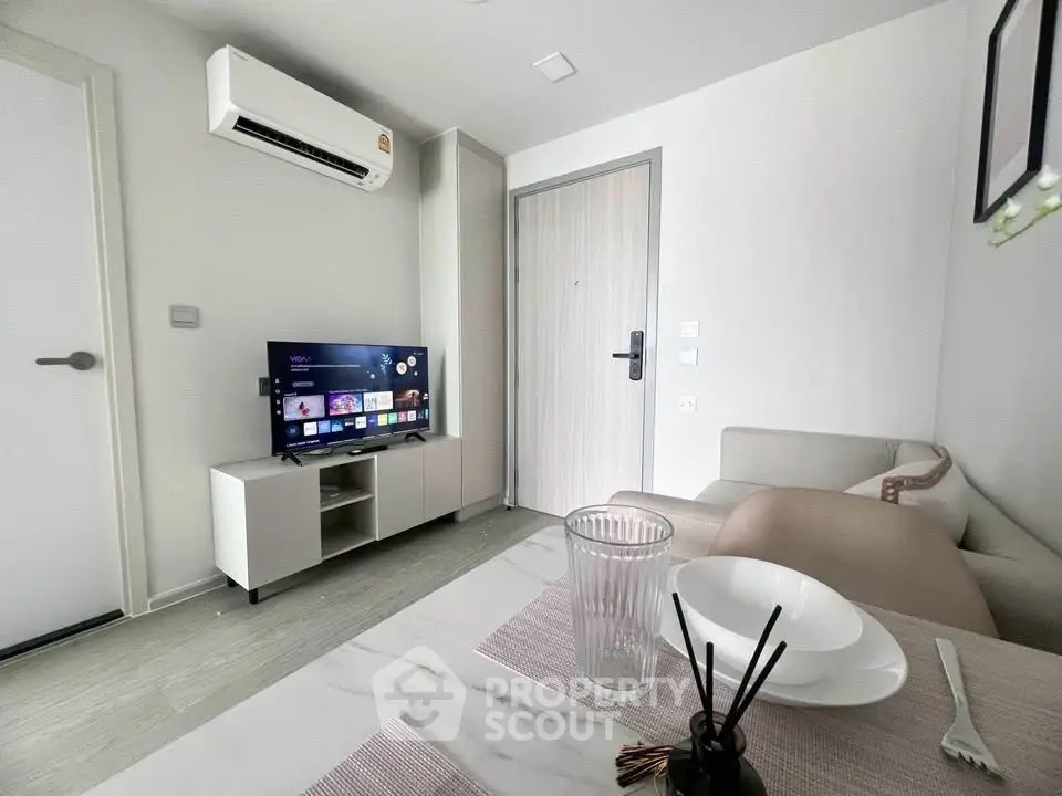 Modern living room with sleek furniture and wall-mounted TV in a cozy apartment.