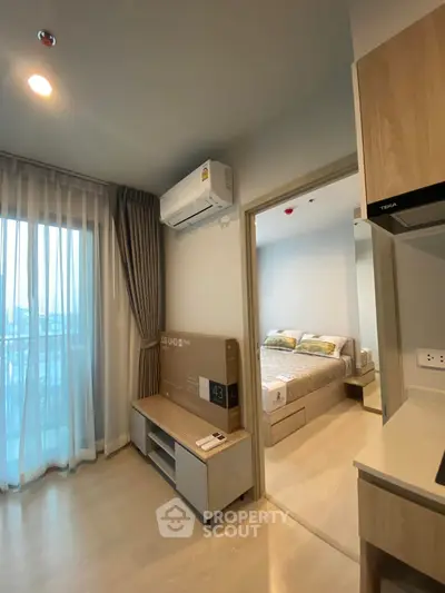 Modern apartment interior with bedroom and living area, featuring natural light and stylish furnishings.