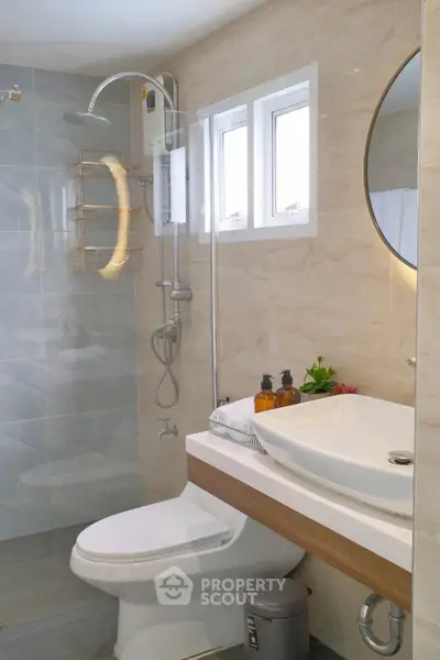 Modern bathroom with sleek fixtures and elegant design, featuring a round mirror and stylish shower area.