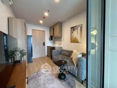 Modern living room with stylish decor and compact kitchen in open layout apartment.