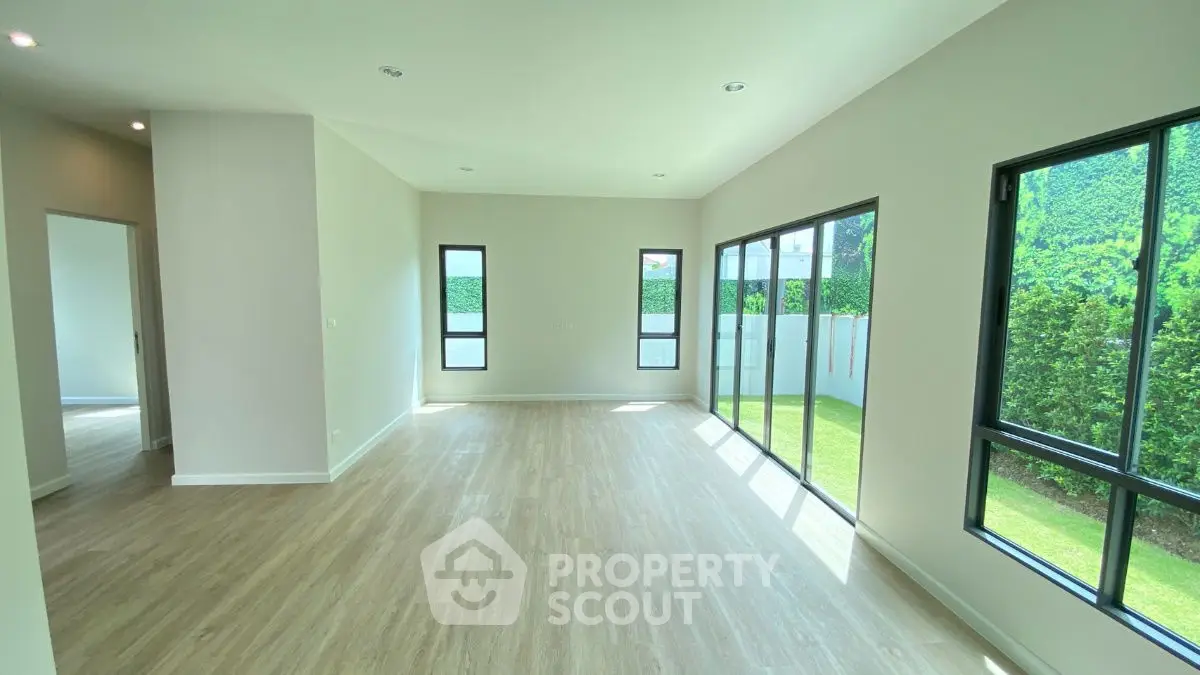 Spacious sunlit living room with large windows and garden view