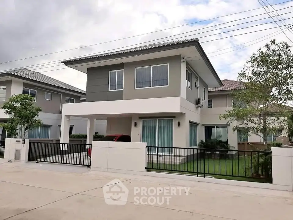 Modern two-story house with sleek design and spacious driveway in a suburban neighborhood.