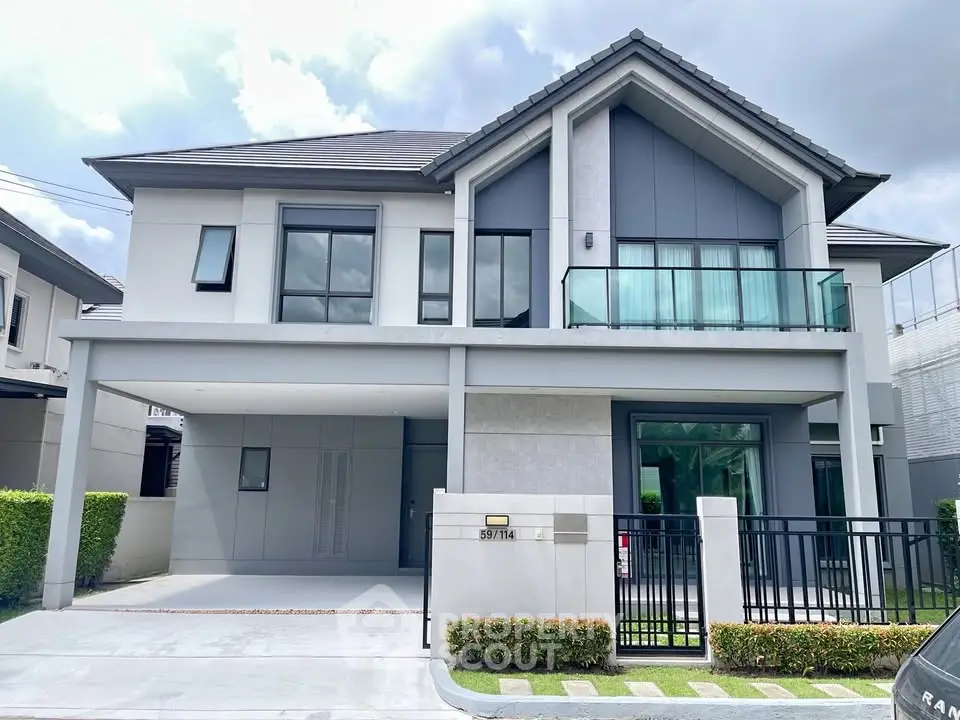 Modern two-story house with sleek design and spacious balcony in a suburban neighborhood.