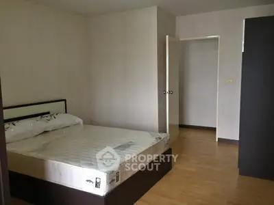 Spacious bedroom with wooden flooring and modern bed frame in a minimalist style.