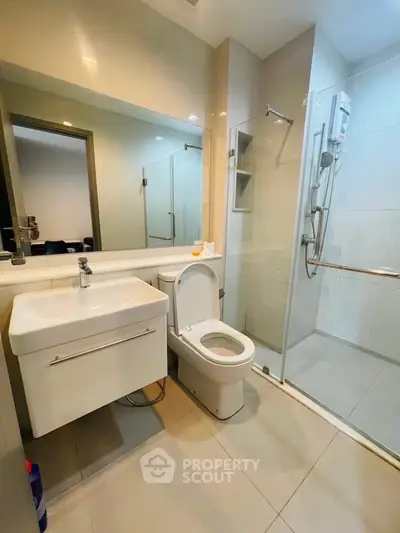 Modern bathroom with sleek fixtures and glass shower enclosure in a contemporary apartment.