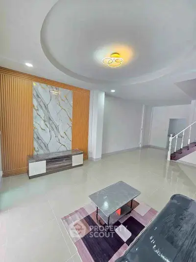 Spacious modern living room with elegant marble accent wall and stylish lighting.