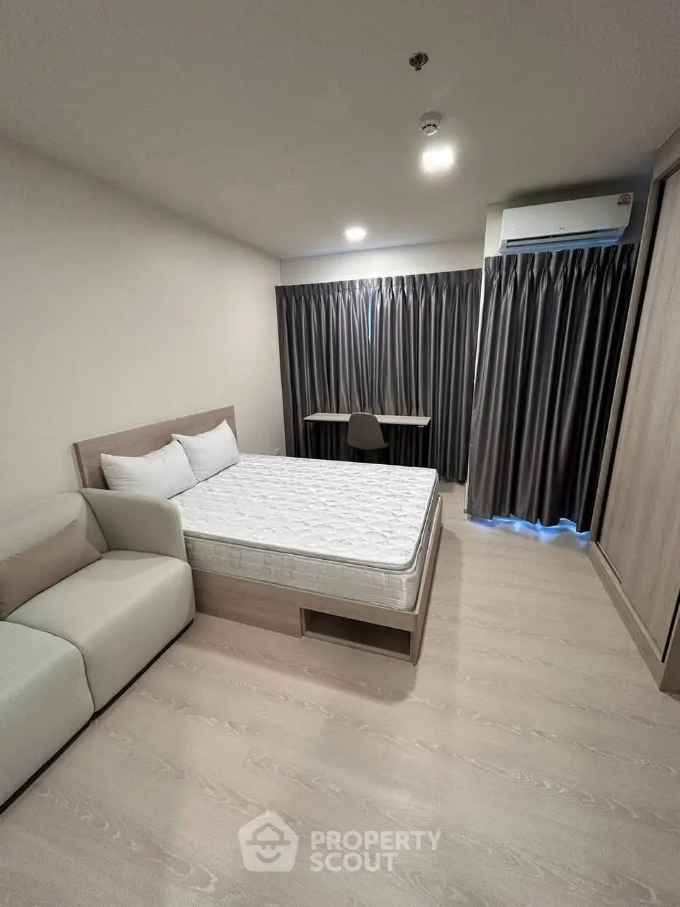 Modern bedroom with minimalist design, featuring a cozy bed, sofa, and study desk.