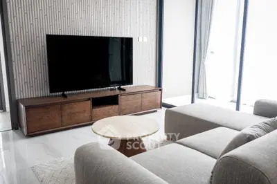 Modern living room with sleek furniture and large TV, featuring a stylish wooden cabinet and natural light.