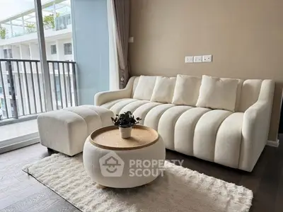 Stylish living room with modern white sofa and balcony view in luxury apartment.