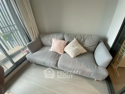 Cozy living room with modern gray sofa and soft pillows by large window