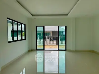 Spacious living room with large windows and sliding doors offering natural light and outdoor view.