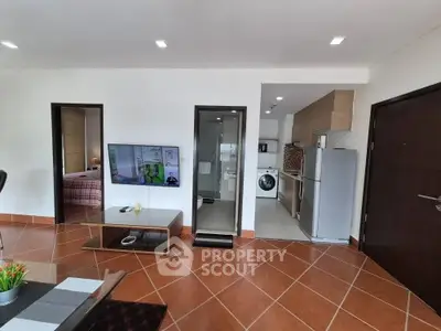 Modern open-plan living room with kitchen and laundry area, featuring sleek appliances and stylish decor.