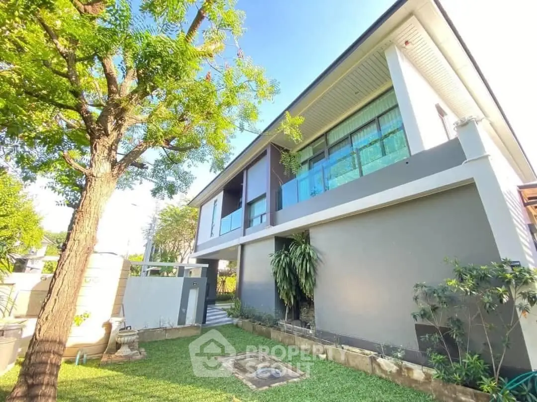 Modern two-story house with lush garden and large windows, perfect for family living.