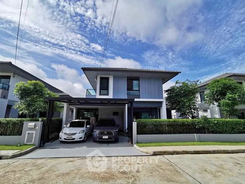 Modern two-story house with driveway and lush greenery in a serene neighborhood.